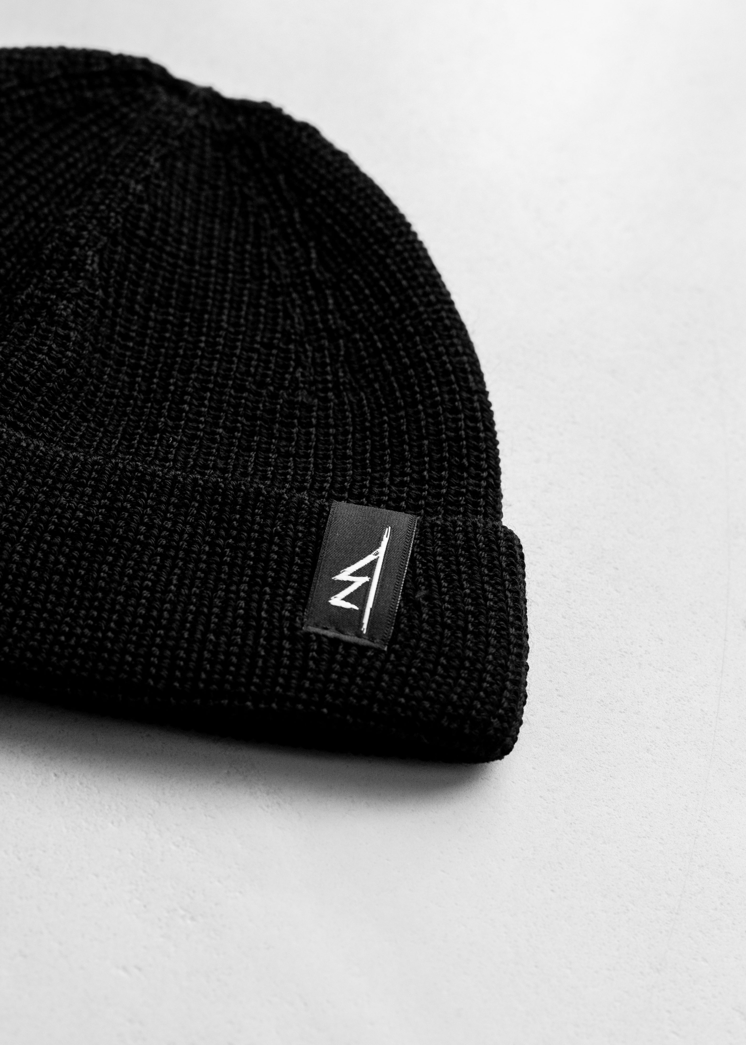 Bies Clothing moda alternatywna polski streetwear. Krótka czapka z włoskiej wełny z merynosów w kolorze czarnym. Wysokość po zawinięciu to 15cm, a szerokość to 23cm. Dodatkowo po lewej stronie znajduje się dyskretna metka z naszym logo.