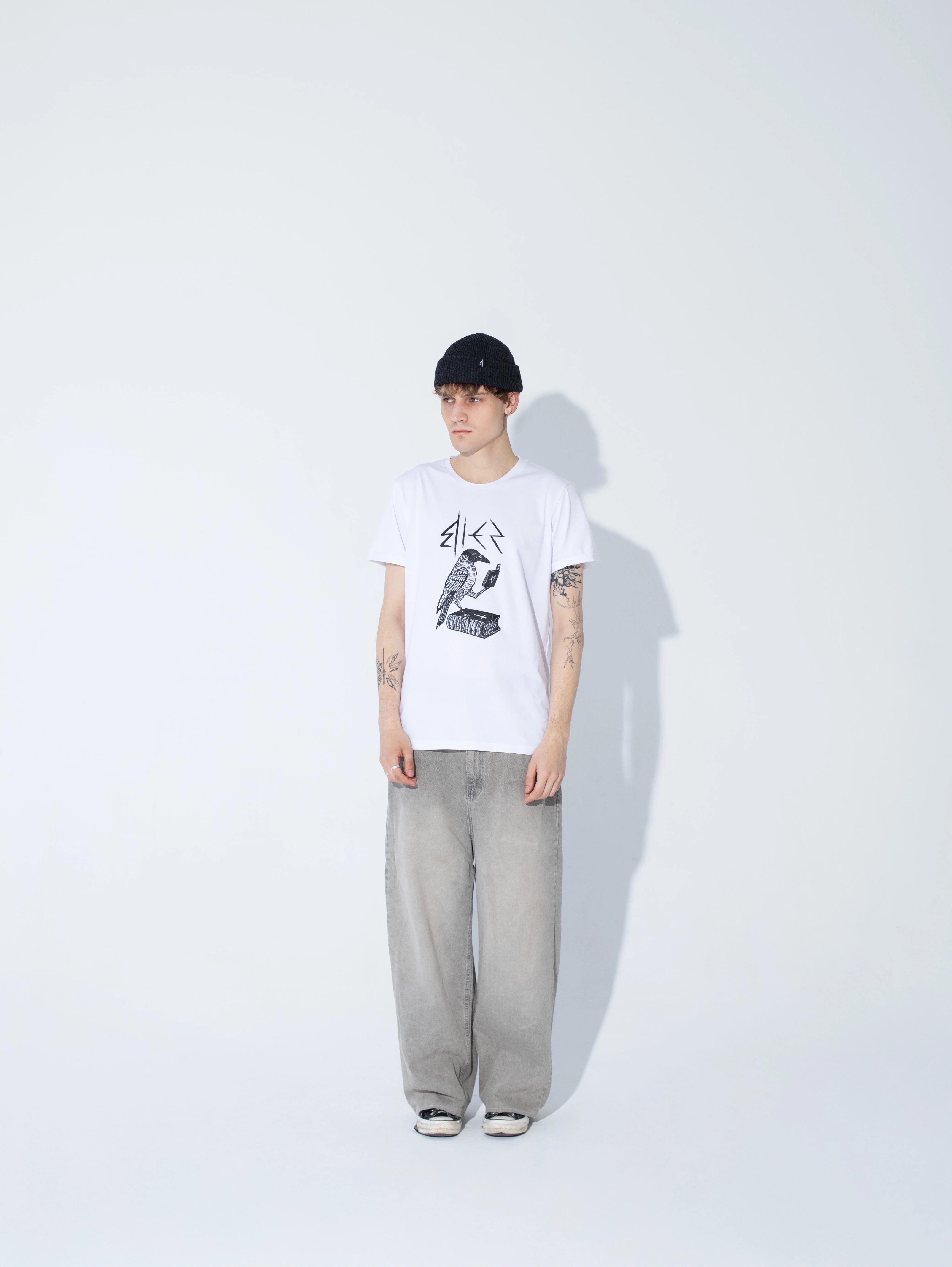 model ubrany w biały t-shirt z krukiem od bies clothing polskiej marki streetwear w stylu goth, rock, numetal. moda alternatywna produkowana w Polsce  